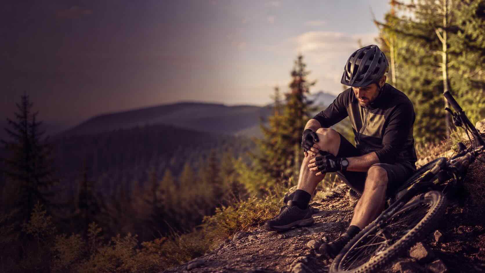 Mountainbiker prüft nach einem Sturz sein verletztes Knie